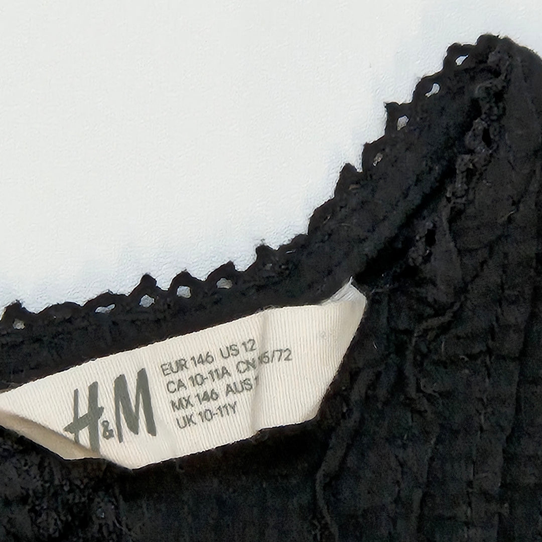 Elegant svart H&M blus med dekorationsdetaljer