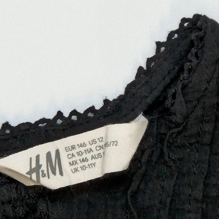 Elegant svart H&M blus med dekorationsdetaljer