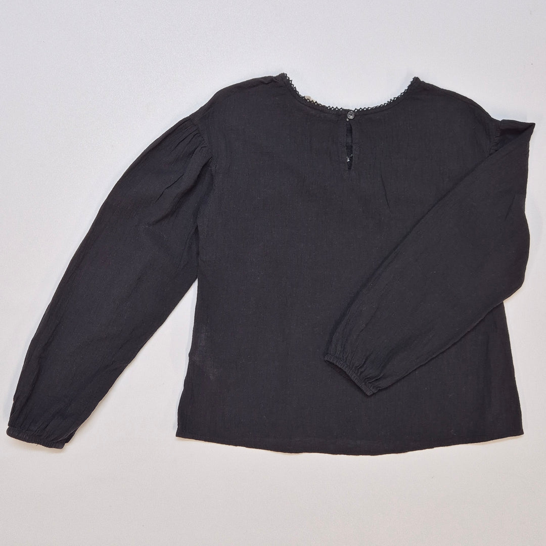 Elegant svart H&M blus med dekorationsdetaljer