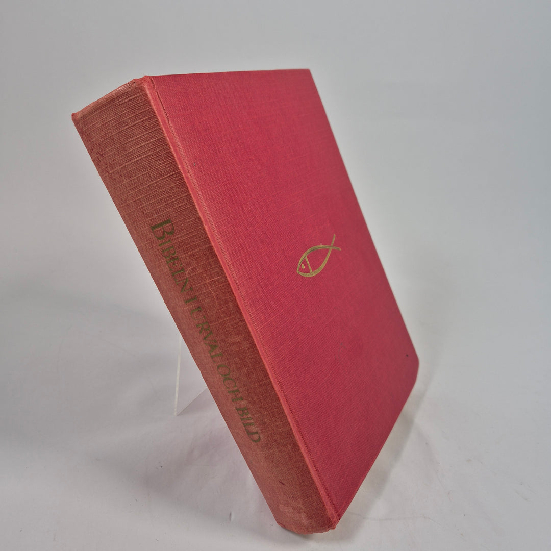 Bibel i röd tyginbunden utgåva med guldfärgad fisk-symbol