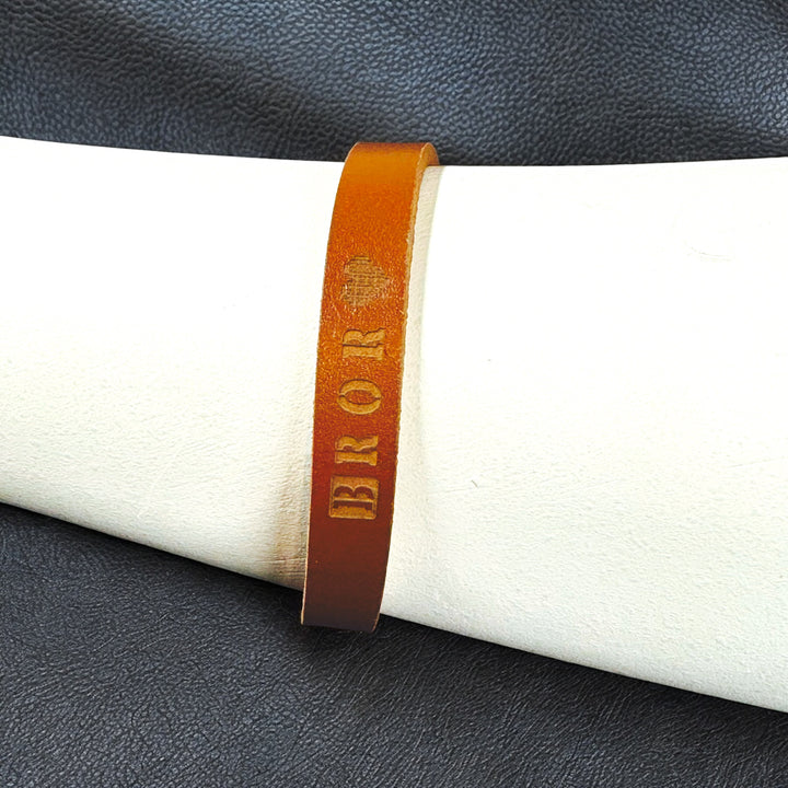 Brun armband med text “BROR”